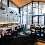 Extension avec toit en verre et grande baie vitrée de la brasserie Maison B à Bridel donnant sur la forêt.