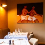 Ambiance feutrée d'une table dressée devant une œuvre d'art à la brasserie Maison B à Bridel.
