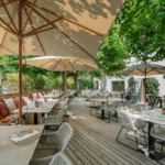 Vue d'ensemble de la terrasse ensoleillée et accueillante du restaurant Maison B à Bridel.
